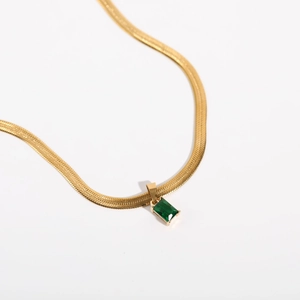 Detailed macro view of 18K gold plated snake chain with square green zircon pendant