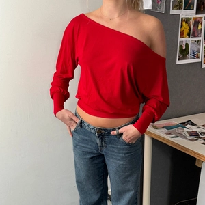 Detail of red off-shoulder long sleeve top with batwing sleeves and elastic cuffs