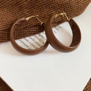 Detail shot of deep brown leather hoop earrings with visible stitching and gold metal clasps