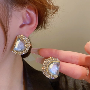 Gros plan détaillé de grandes boucles d'oreilles D dorées avec cristaux et pierre facettée