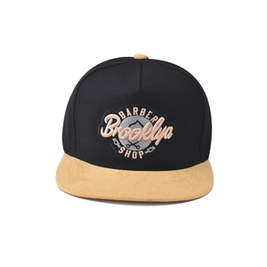 Close-up of BARBER Brooklyn SHOP embroidered patch on a black and tan snapback cap