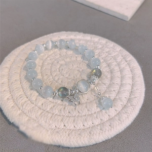 Détail macro du bracelet en pierre œil de chat avec pompons argentés et perles