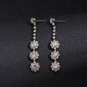 Detailed view of silver dangle earrings with sparkling rhinestones and floral accents