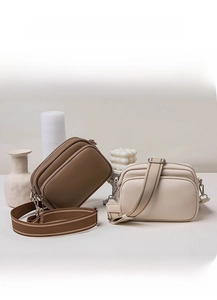Detail view of large capacity crossbody camera bags in brown and beige textured leather