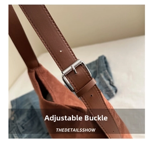 Detail of the adjustable silver metal buckle on a brown suede shoulder tote bag