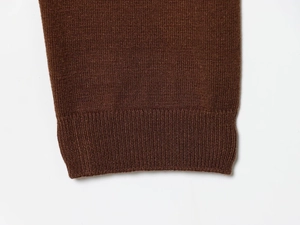 Macro shot of dark brown knitted sweater cuff with ribbed edge detail and fine textures