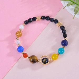 Macro view of blue sandstone beads and gold Sagittarius charm on woven bracelet
