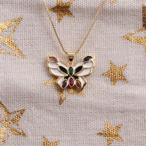 Détail du pendentif papillon doré orné de pierres multicolores et d'émail blanc