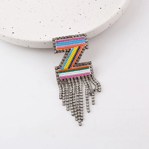 Macro shot of colorful embroidered Z-shaped brooch with shimmering rhinestone tassels