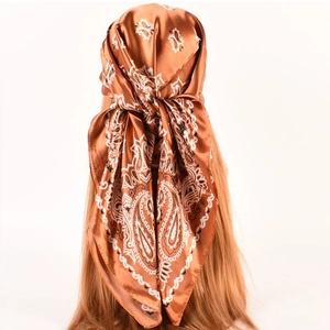 Detail of a brown paisley silk satin headscarf tied on a mannequin with golden hair