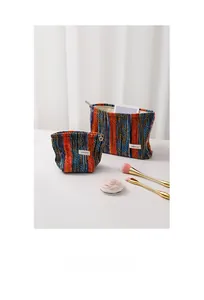 Close-up of bohemian striped knitted makeup bags with a decorative gold flower zipper puller