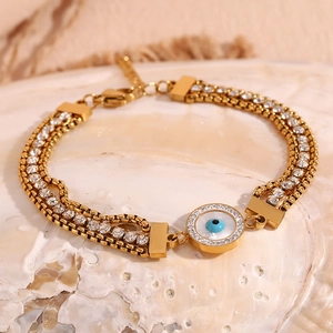 Detailed macro view of triple-strand gold chain bracelet with evil eye charm