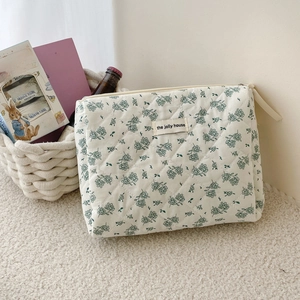 Detailed close-up of quilted floral cosmetic bag featuring a woven label and brass zipper