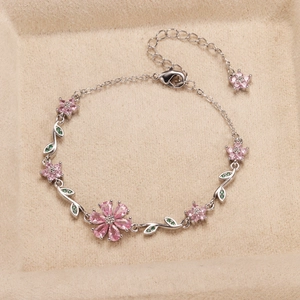 Close-up of a silver flower bracelet with pink zircon stones on a beige velvet tray