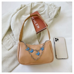 Detail of beige shoulder bag featuring silver metal chain with blue butterfly charms