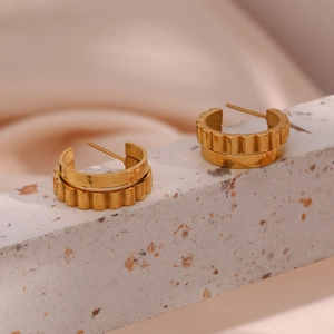Macro view of gold C-shaped earrings featuring a polished double-layer gear edge design