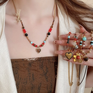 Close-up of vintage brown tiger eye stone necklace with gold bow and heart charms