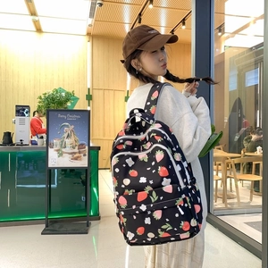 Back view of a black backpack with cute strawberry prints worn by a model in a shop