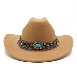 Détail d'un chapeau de cowboy avec bandeau ethnique tressé, pompons et pierre turquoise