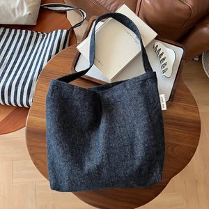 Detailed view of the dark blue denim tote bag texture and its minimalist brand label