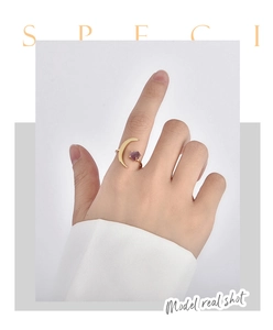 Detailed view of a gold moon ring with a raw purple amethyst stone on a model's hand
