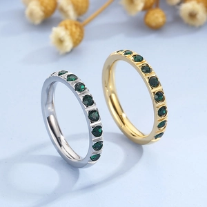 Detail of gold and silver titanium rings with embedded green zircon stones on blue surface