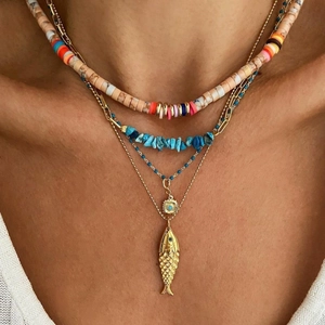 Detail of layered bohemian necklace with turquoise beads, clay discs and fish pendant
