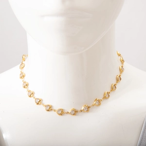 Detailed view of a gold heart-shaped necklace with clear gems on a female mannequin torso
