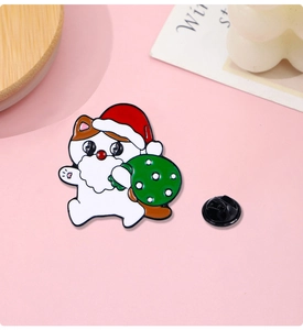 Detail of Christmas cat enamel pin featuring a Santa hat and a green gift bag