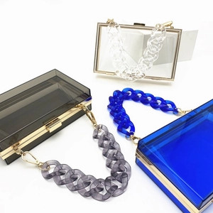 Detailed top view of three acrylic evening bags in grey, clear, and blue with gold hardware