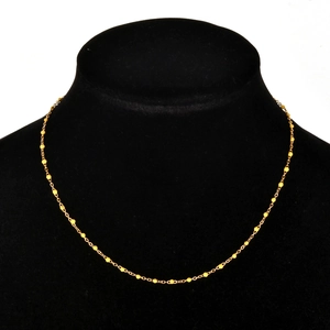 Detail of a minimalist gold bead chain necklace displayed on a black jewelry bust stand
