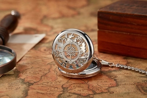 Detail of silver pocket watch with compass design on vintage map background