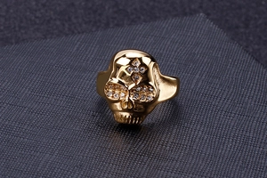 Detailed macro view of a gold skull ring featuring a cross pattern and pave crystal eyes