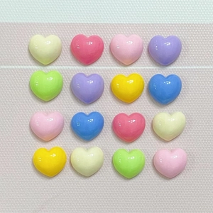 Detailed grid of sixteen colorful heart-shaped resin charms on soft pink fabric