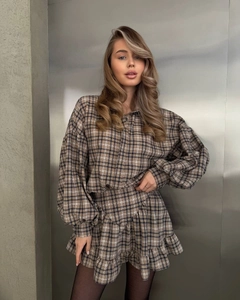Detailed view of women's plaid two-piece set with ruffled mini skirt and long sleeve top