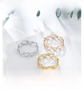 Detailed view of hollow heart rings in silver, gold, and rose gold on marble base
