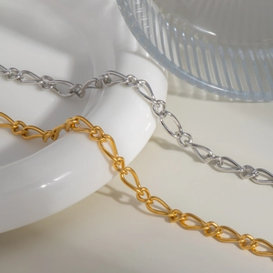 Detail of infinity link anklets in gold and silver finish on elegant white ceramic