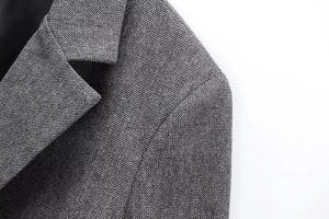 Close-up of grey herringbone wool blend blazer showing premium lapel stitching and texture