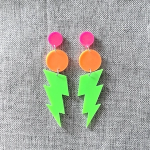 Detailed flat lay of neon acrylic lightning bolt earrings on linen background
