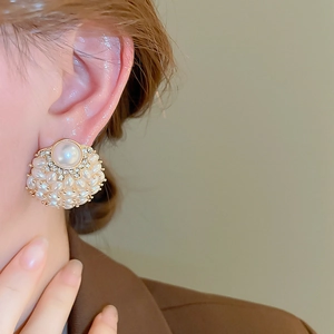 Close-up of elegant floral pearl cluster earrings worn on ear with gold and diamond details