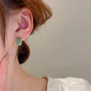 Detail of vintage green rectangular stud earring with gold border on a female model