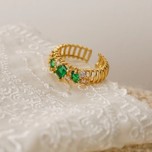 Macro shot of gold-plated ring with green marquise zircon on white lace fabric