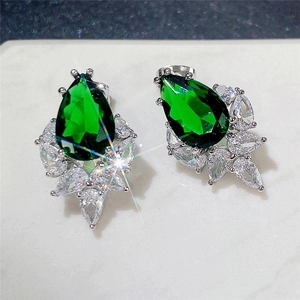 Macro detail of emerald-cut pear-shaped green earrings with marquise zircon stones