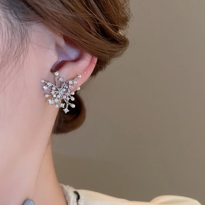 Close-up of elegant snowflake stud earrings with white pearls and zircons on model