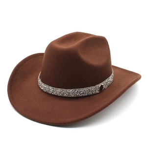 Detail of a brown felt cowboy hat featuring a sparkling rhinestone band and M metal emblem
