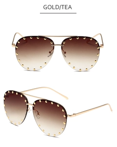 Detail view of gold aviator sunglasses with tea gradient lenses and metal rivet accents