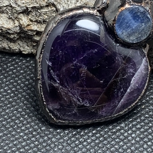 Macro detail of vintage heart amethyst and blue crystal pendant with antique bronze plating