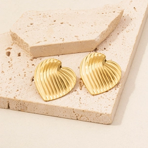 Macro view of gold heart earrings featuring unique ribbed textures on natural stone