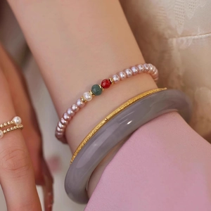 Close-up of stacked freshwater pearl bracelets with agate beads and a gold relief bangle
