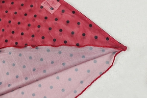 Detail of red mesh fabric with black polka dots showing premium stitching and S size label